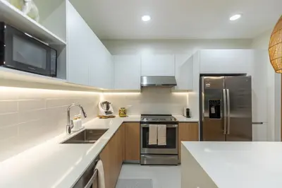 a kitchen with white cabinets and a stainless steel refrigerator at Pura Vida Peaceful Condo At Become Nosara in Nicoya