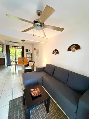 a living room with a blue couch and a ceiling fan at Pineapple Condo at Villa Riviera in Coco