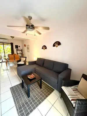 a living room with a blue couch and a table at Pineapple Condo at Villa Riviera in Coco
