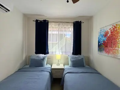 two beds in a small room with a window at Sunscape Second Floor Condo with Rooftop in Coco