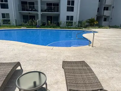 a swimming pool with two chairs and a building at 2BR with ocean view in Jacó