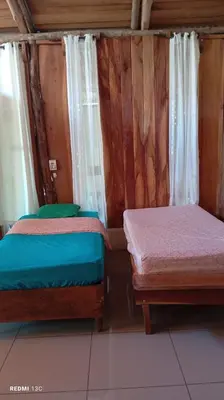 two beds in a room with wooden walls at Helenors estancia in Nicoya