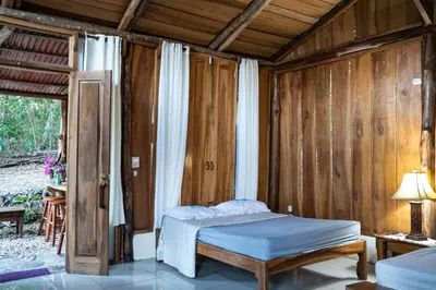 a bedroom with a bed in a room with wooden walls at Helenors estancia in Nicoya