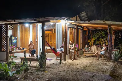 a group of people sitting on a porch at night at Helenors estancia in Nicoya