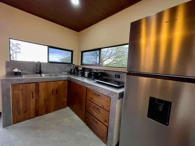 a kitchen with a stainless steel refrigerator and wooden cabinets at Villa Macua Private Pool and Bird Watching in Fortuna