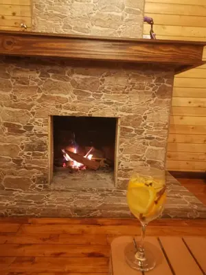 a glass of wine next to a fireplace at Cabaña de montaña in Cañón