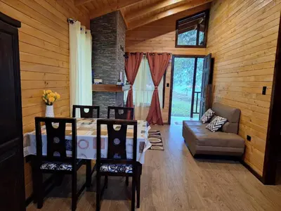 a dining room with a table and chairs and a couch at Cabaña de montaña in Cañón