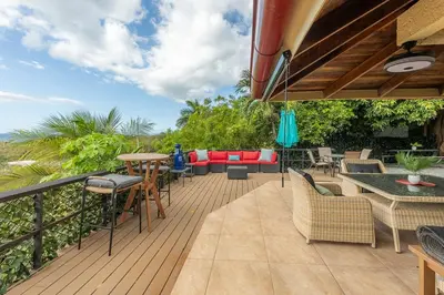 a deck with a couch and tables and chairs at Villa Sunrise - Incredible Ocean Views! in Ocotal
