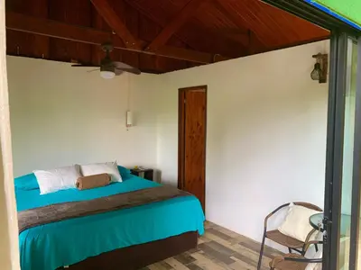 a bedroom with a bed and a chair at Luna Escondida in Sarapiquí