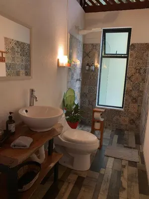 a bathroom with a toilet and a sink and a window at Luna Escondida in Sarapiquí