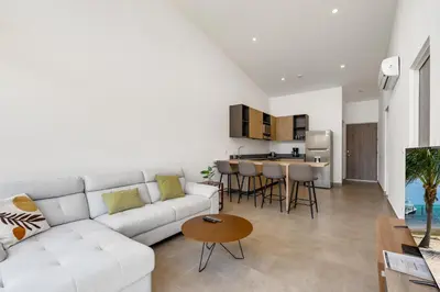 a living room with a white couch and a table at 8-min Walk to Beach with Pool & Golf in Pochote