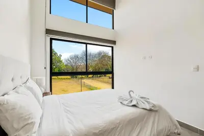 a bedroom with a bed and a large window at 8-min Walk to Beach with Pool & Golf in Pochote