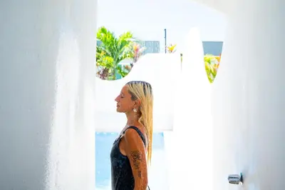 a woman with a tattoo on her arm looking out a window at Casa Anbara Private Pool in Pochote