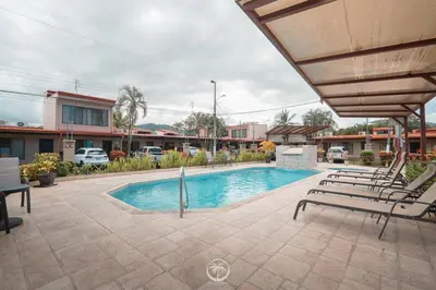 a swimming pool with lounge chairs next to a building at Cosy condo in Jaco Park, 450m from the beach 6pax in Jacó