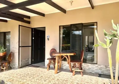 a wooden table and chairs in front of a house at Cosy condo in Jaco Park, 450m from the beach 6pax in Jacó