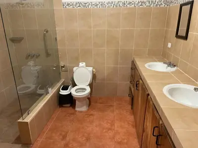 a bathroom with a toilet and two sinks and a shower at villa Alcaravan - 4 rooms home in Lagunillas
