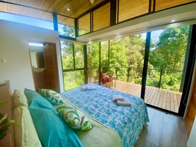a bedroom with a bed in front of a large window at Sinfonía Tropical, ocean view, 5 minutes driving to Playa Linda, 15 to Dominical, wifi Starlink in Savegre