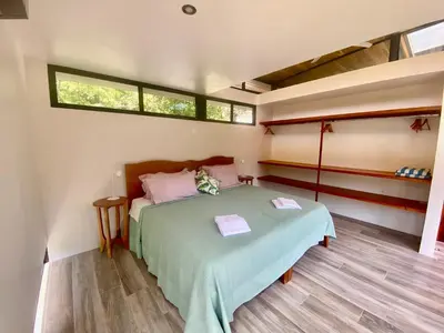 a bedroom with a green bed in a room with windows at Sinfonía Tropical, ocean view, 5 minutes driving to Playa Linda, 15 to Dominical, wifi Starlink in Savegre