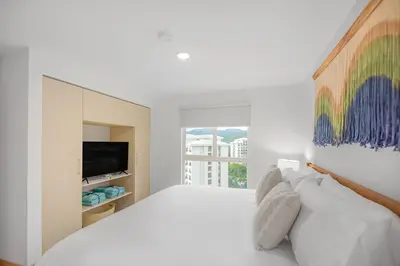 a white bedroom with a large bed and a television at Upstay - New Condo Just Steps Away from the Beach in Jacó