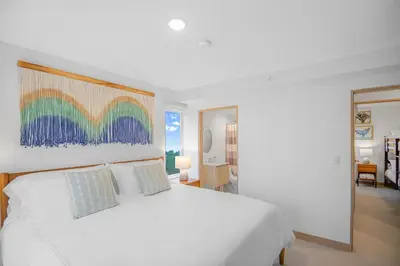 a bedroom with a white bed with a painting on the wall at Upstay - New Condo Just Steps Away from the Beach in Jacó