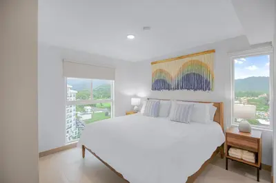 a white bedroom with a large bed and a window at Upstay - New Condo Just Steps Away from the Beach in Jacó