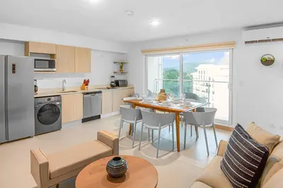 a kitchen and living room with a table and chairs at Upstay - New Condo Just Steps Away from the Beach in Jacó