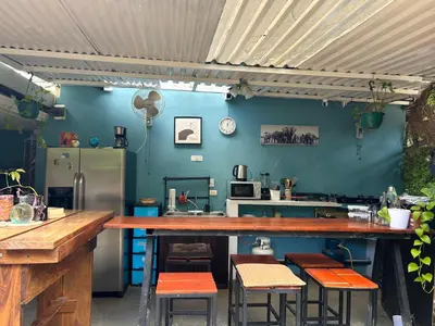 a kitchen with a counter with chairs and a refrigerator at The Backside House - Women Only - in Tamarindo