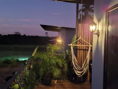 a porch with a hammock on the side of a house at Arenal Tiny Lodge #1 in San Francisco