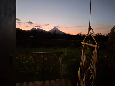 a sunset from a balcony with a mountain in the background at Arenal Tiny Lodge #1 in San Francisco