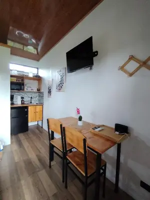 a dining room table with chairs and a television on the wall at Arenal Tiny Lodge #1 in San Francisco