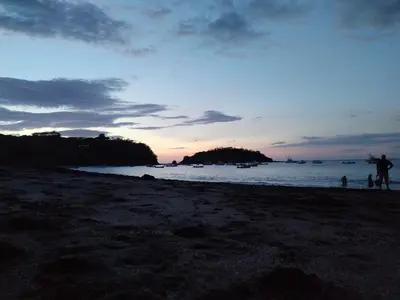 a group of people on a beach at sunset at Casa vacacional Brisa Del Mar in Coco