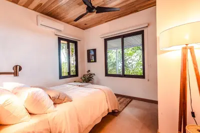 a bedroom with a bed and two windows at Arbórea Villas in Chontales