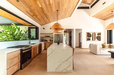 an open kitchen with wooden ceilings and a large island at Arbórea Villas in Chontales