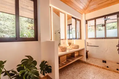 a bathroom with a sink and a shower with windows at Arbórea Villas in Chontales