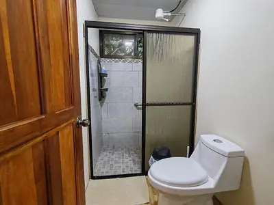 a bathroom with a toilet and a shower with a shower at Villas Los Titos in La Fortuna in San Francisco