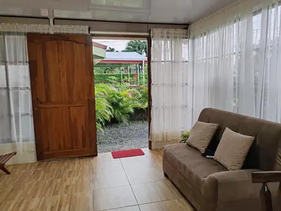 a living room with a couch and a wooden door at Villas Los Titos in La Fortuna in San Francisco