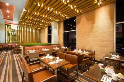 a restaurant with wooden tables and chairs in a room at Hilton Garden Inn San Jose La Sabana, Costa Rica in San José