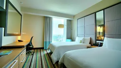 a hotel room with two beds and a desk at Hilton Garden Inn San Jose La Sabana, Costa Rica in San José