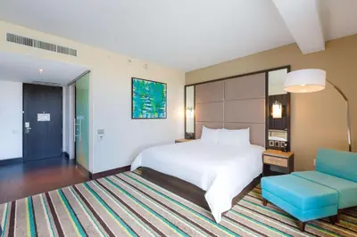 a bedroom with a bed and a blue chair at Hilton Garden Inn San Jose La Sabana, Costa Rica in San José