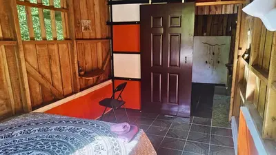 a bedroom with a bed and a door and a chair at Wild Nest Chirripo in Rivas