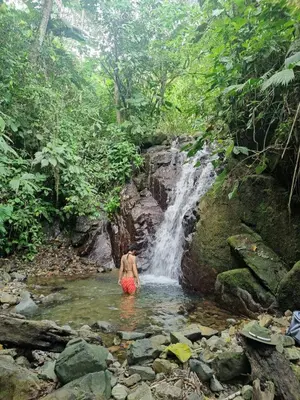 a man standing in a stream in front of a waterfall at Wild Nest Chirripo in Rivas