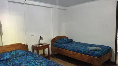 a room with two beds and a table with a lamp at Hotel Marielos Tamarindo in Tamarindo