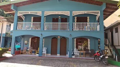 a blue house with a balcony and a motorcycle parked in front at Hotel Marielos Tamarindo in Tamarindo