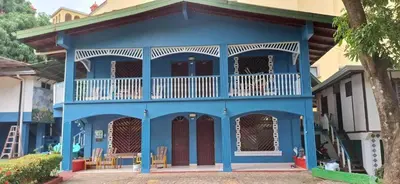 a blue house with a balcony on a street at Hotel Marielos Tamarindo in Tamarindo