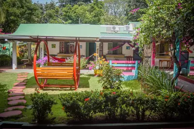 a park with a swing and a house with flowers at Hotel Marielos Tamarindo in Tamarindo