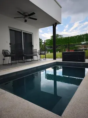 a swimming pool with chairs and a house at Casa Coral tu refugio ideal in Herradura