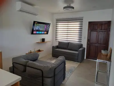 a living room with a couch and a tv at Casa Coral tu refugio ideal in Herradura