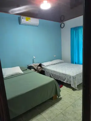 a bedroom with two beds and a blue wall at Casa veranera in Sarapiquí