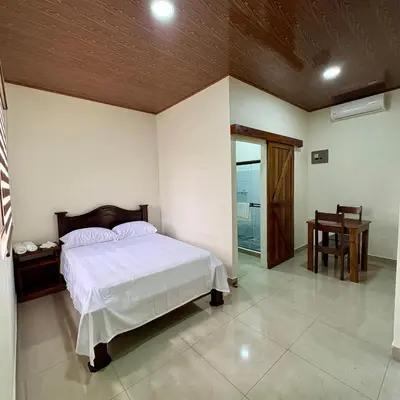 a bedroom with a white bed and a wooden ceiling at Chato Arenal Lodge in Fortuna