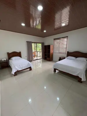 a large room with two beds and a window at Chato Arenal Lodge in Fortuna
